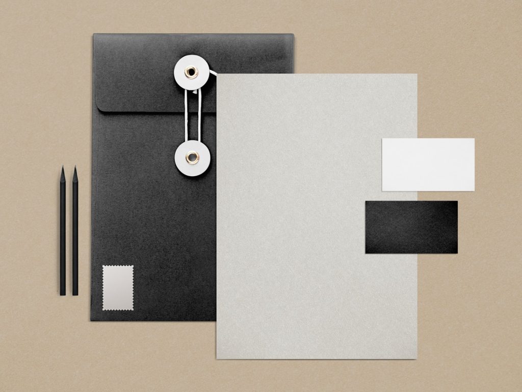 Black envelope, blank letterhead and business cards on a tan background