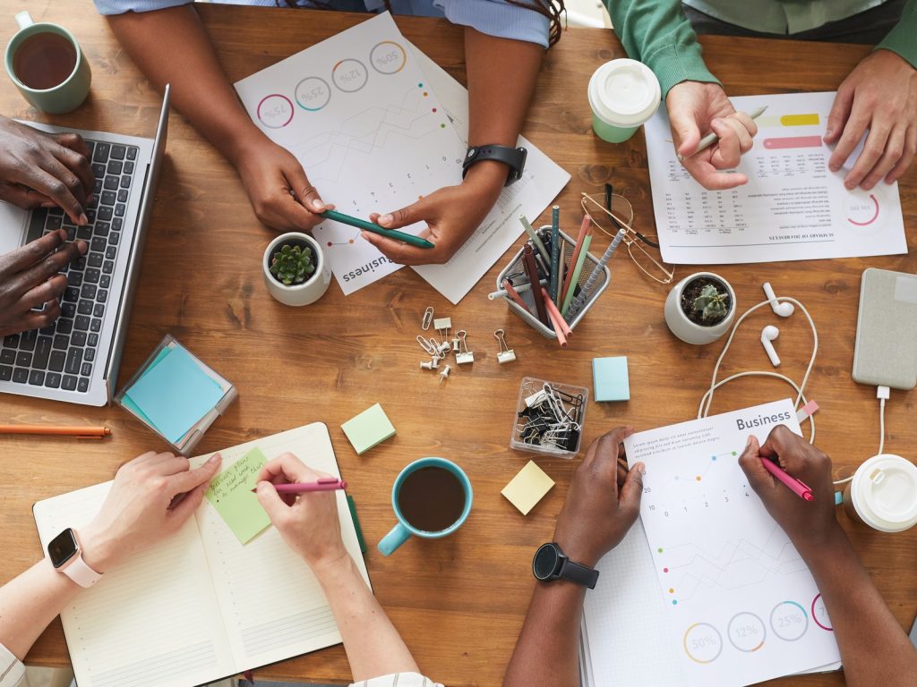 Overhead view of a team brainstorming at a wooden table with laptops and notes