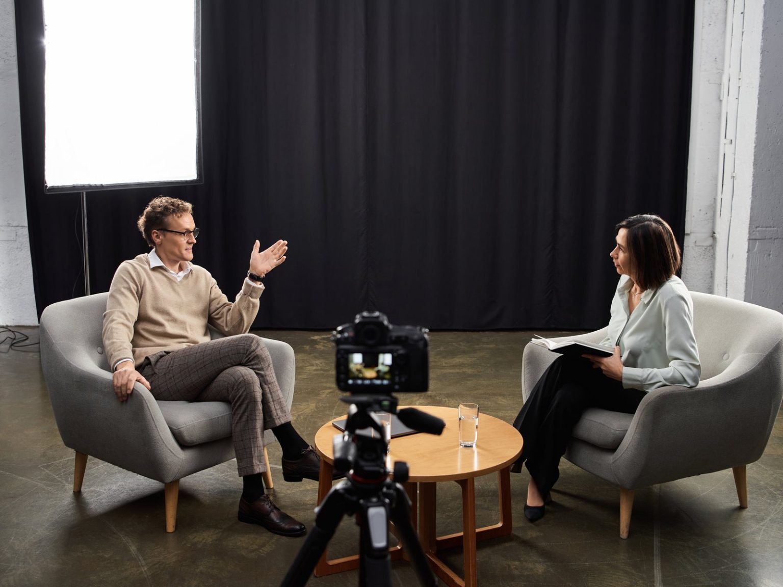 Camera filming an interview between two people in a studio
