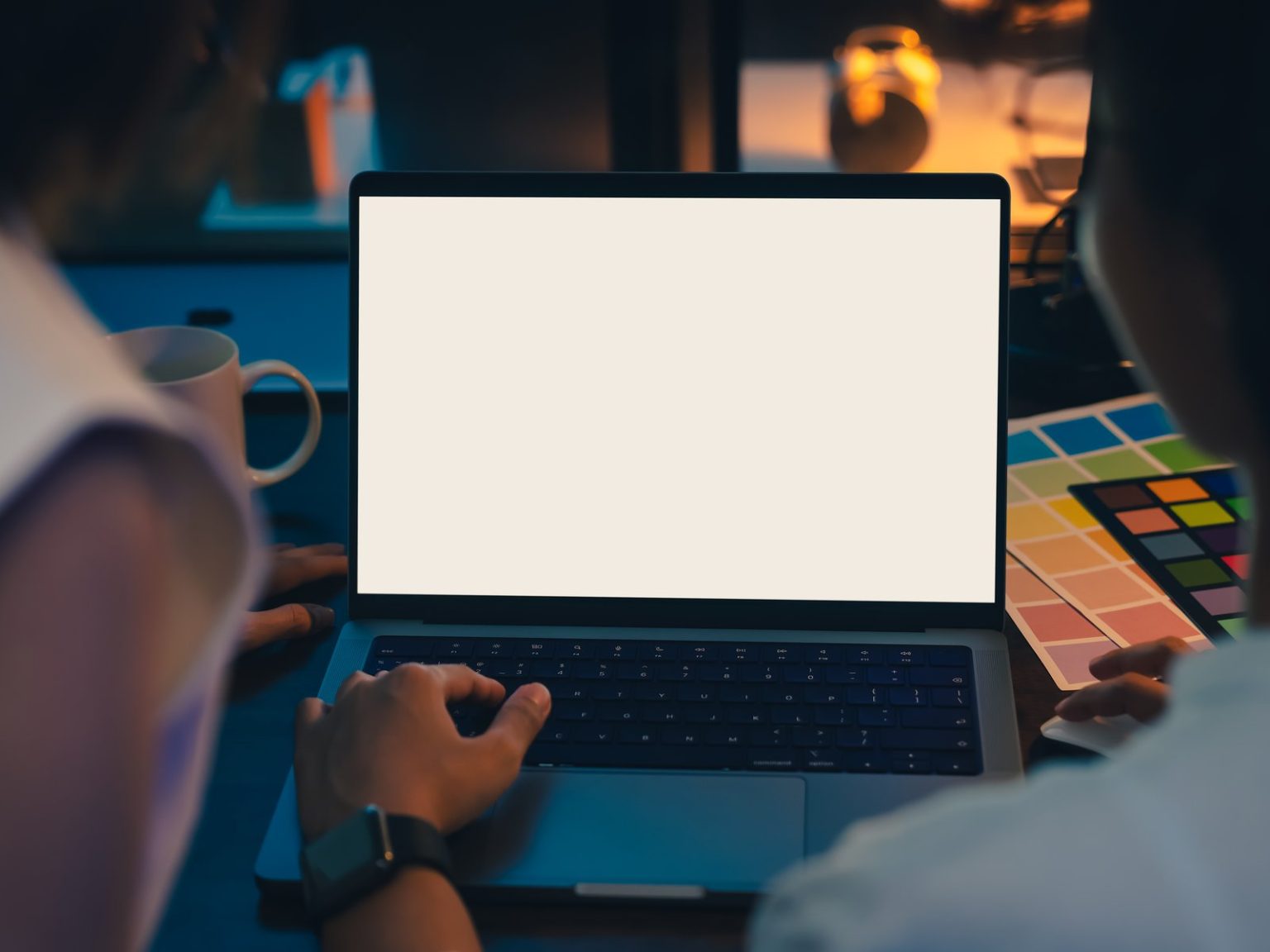Laptop with a blank cream screen on a designer's desk with colour swatches