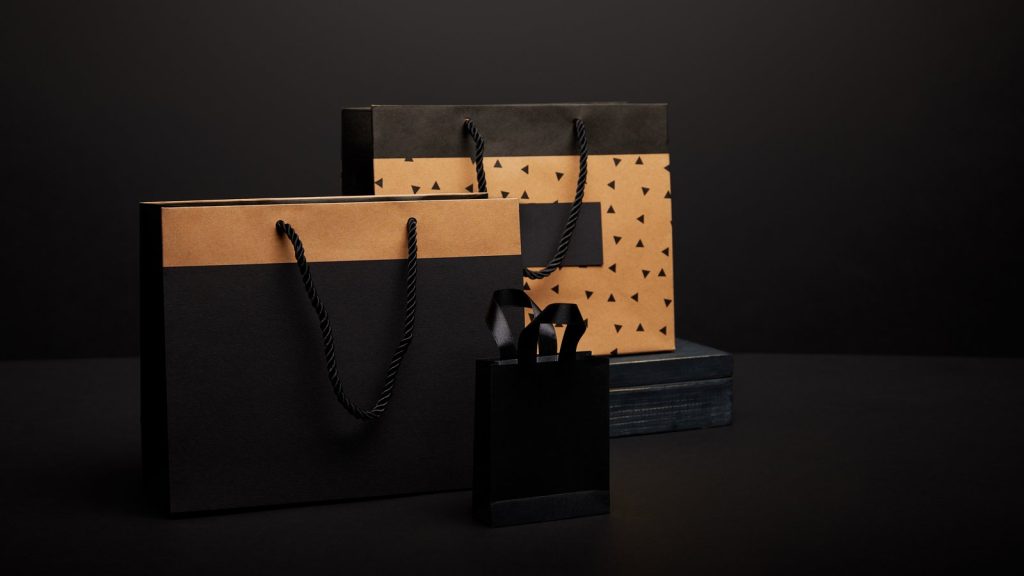 Black and brown paper shopping bags styled on a dark background