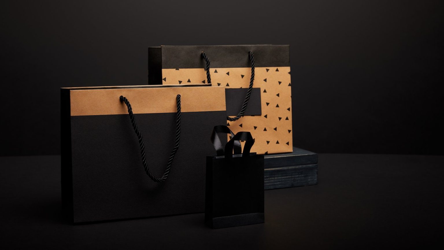 Black and brown paper shopping bags styled on a dark background