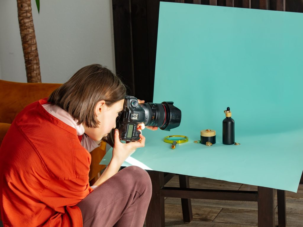 Photographer shooting products against a turquoise backdrop in a studio
