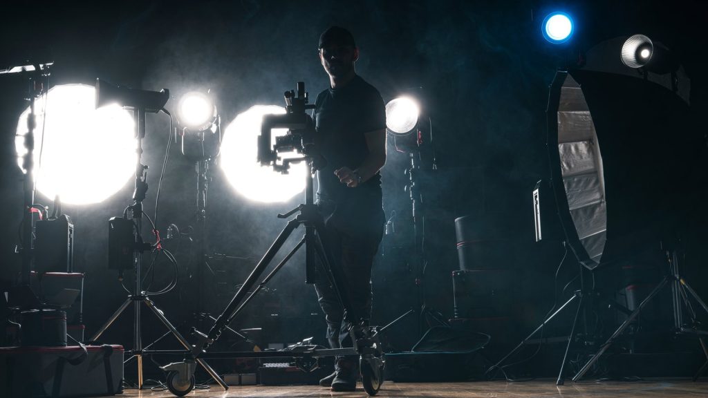 Silhouette of a cinematographer behind a camera with studio lights