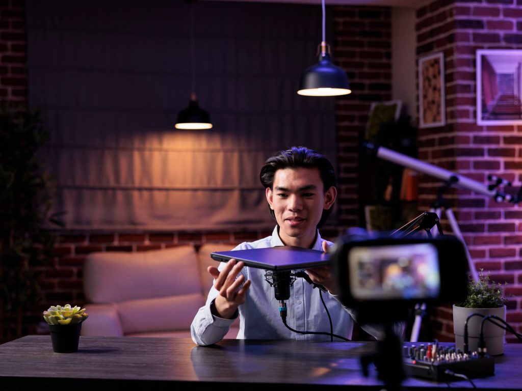 Young man filming himself in a home studio with purple lighting