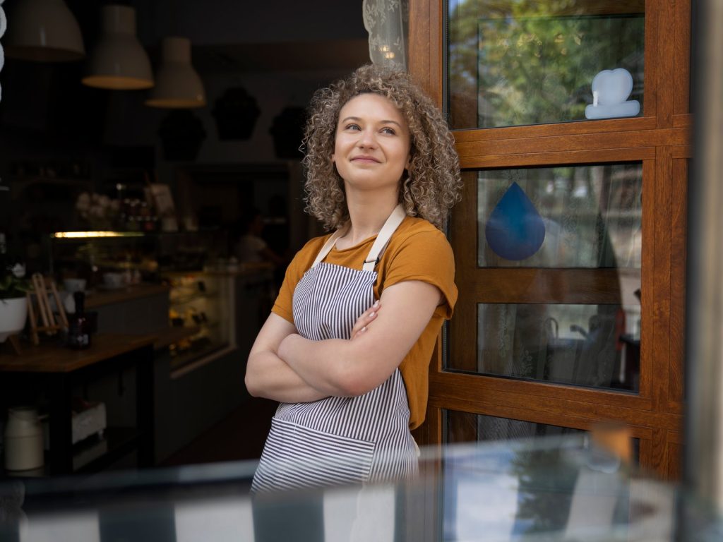 Smiling woman in an apron standing in the doorway of a cafe